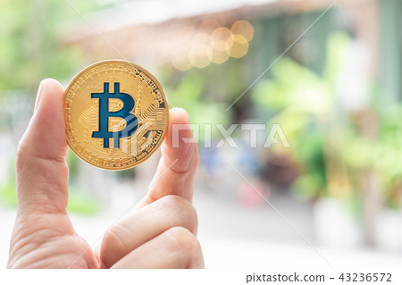 Hand holding gold bitcoin in front of restaurant Hand holding gold bitcoin in front of restaurant 43236572