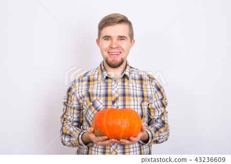 portrait of a young farmer holding a pumpkin on a light background studio portrait of a young farmer holding a pumpkin on a light background studio 43236609