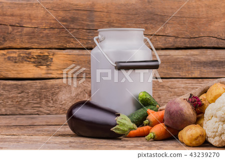 Enameled milk can with handle and raw fresh vegetables. 43239270