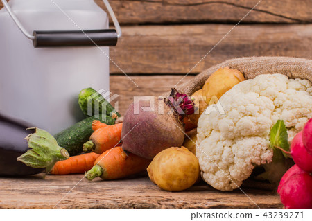 Enamelware milk churn and vegetables close up. Enamelware milk churn and vegetables close up. 43239271