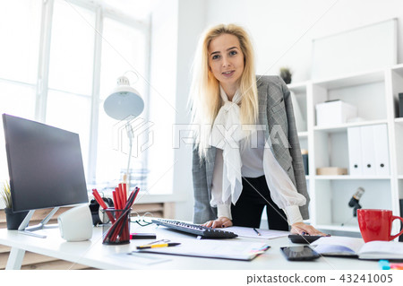 A young girl stands in the office, hands on the table. A young girl stands in the office, hands on the table. 43241005