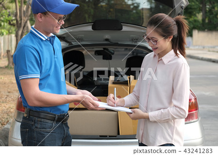 woman signing signature on clipboard to receive package from delivery man. male postal courier person deliver box 43241283