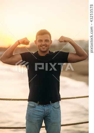 handsome man standing on pier near the sea in sunset time handsome man standing on pier near the sea in sunset time 43253578
