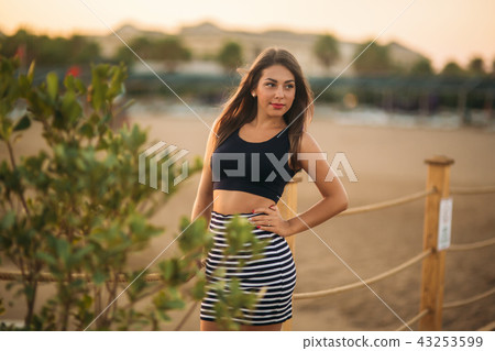 Attractive girl walking on pier near the sea in sunset time Attractive girl walking on pier near the sea in sunset time 43253599