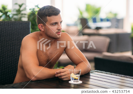 Young man sitting of the beach club bar and drinking tonic 43253754