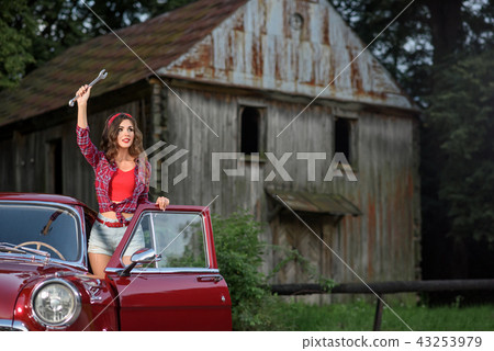 Beatiful pin up girl needing help, keeping a wretch, standing near retro car. 43253979