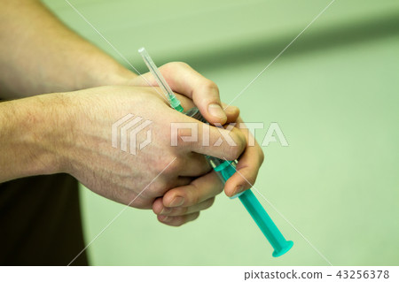 hands holding a syringe hands holding a syringe 43256378