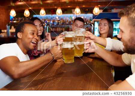 Group of happy friends enjoying beer at pub, toasting and laughing. 43256930