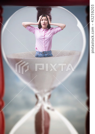 Sad woman inside an hourglass, deadline concept Sad woman inside an hourglass, deadline concept 43259203