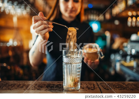 Female barman mixing at the bar counter in pub 43259220