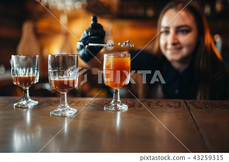 Female bartender prepares alcoholic coctail in pub 43259315