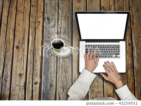Working on his laptop on rustic wooden table Working on his laptop on rustic wooden table 43259551