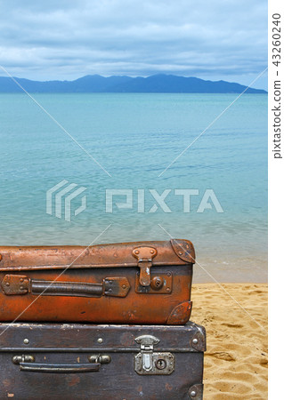 Old vintage travel suitcases over sea beach 43260240