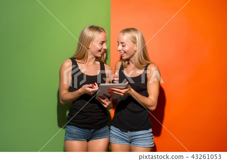 Picture of two young happy women looking at the camera and holding laptop. Picture of two young happy women looking at the camera and holding laptop. 43261053