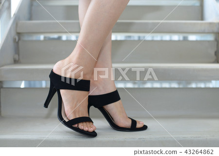 Women's feet wearing high-heeled sandals Women's feet wearing high-heeled sandals 43264862