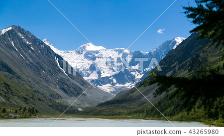 A mountain with a white peak near the lake. A mountain with a white peak near the lake. 43265980