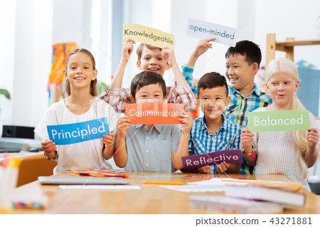 Smiling schoolschildren standing in the middle of a classroom Smiling schoolschildren standing in the middle of a classroom 43271881