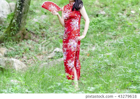 A woman in a Chinese dress standing in the forest A woman in a Chinese dress standing in the forest 43279618