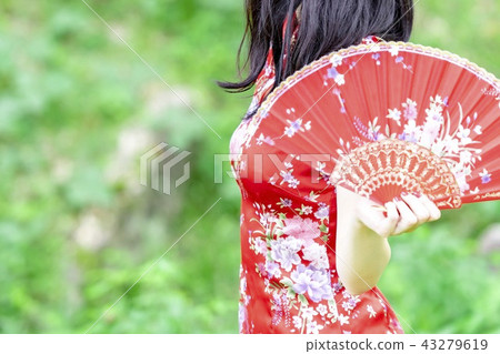 A woman in a Chinese dress standing in the forest A woman in a Chinese dress standing in the forest 43279619