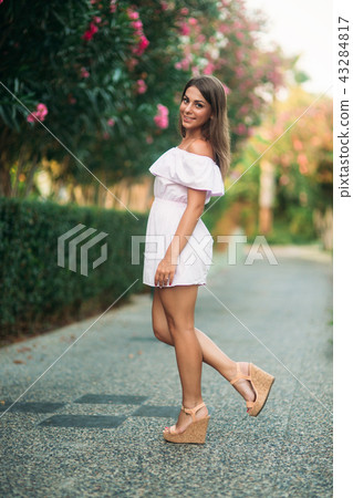 Sexy lady in white dress standing near the flowers Sexy lady in white dress standing near the flowers 43284817