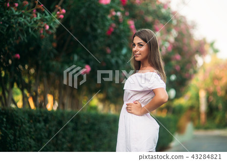 Sexy lady in white dress standing near the flowers 43284821