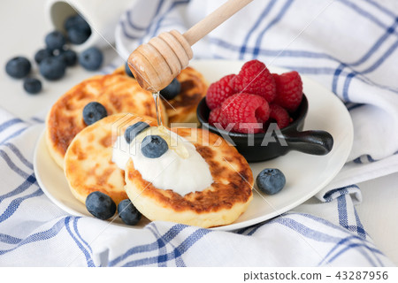 Cottage cheese pancakes or sirniki with sour cream and berries Cottage cheese pancakes or sirniki with sour cream and berries 43287956