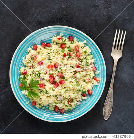 Tabbouleh salad with couscous and pomegranate seeds on a blue plate 43287966