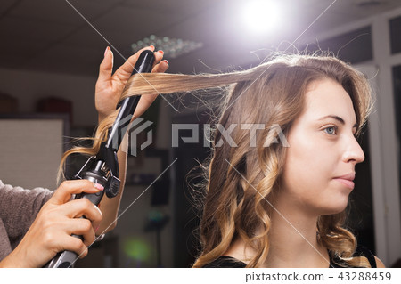 hairdresser carefully making hair curling to a client hairdresser carefully making hair curling to a client 43288459