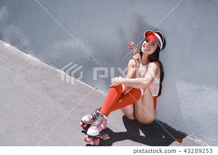Happy beautiful young woman riding on rollers, eating candy. Summer photo. Happy beautiful young woman riding on rollers, eating candy. Summer photo. 43289253