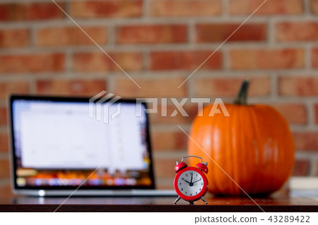 Little alarm clock on a table with pumpkin Little alarm clock on a table with pumpkin 43289422