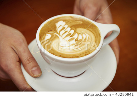 Man carrying a cafe latte with latte art drawn 43290941