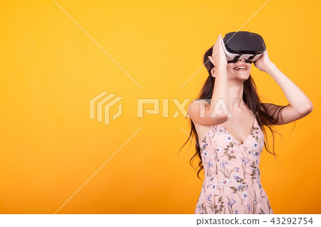 Girl plays vr game in virtual reality helmet in studio over yellow background Girl plays vr game in virtual reality helmet in studio over yellow background 43292754