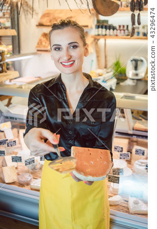 Beautiful woman offering cheese on delicatessen counter Beautiful woman offering cheese on delicatessen counter 43296474