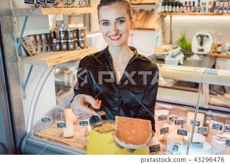 Beautiful woman offering cheese on delicatessen counter 43296476