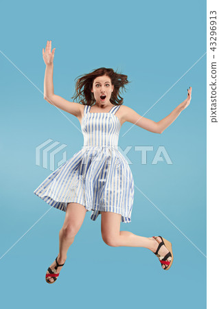 Freedom in moving. Pretty young woman jumping against blue background Freedom in moving. Pretty young woman jumping against blue background 43296913