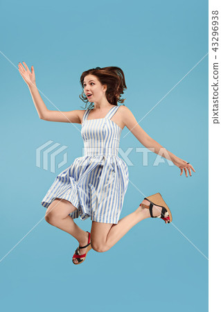 Freedom in moving. Pretty young woman jumping against blue background 43296938