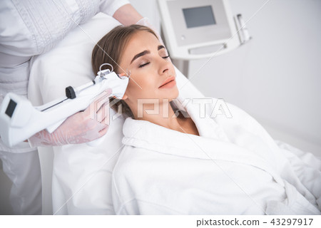 Serene young lady receiving injection in temple 43297917