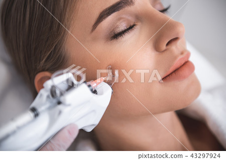 Beautiful young lady getting injection in cheek 43297924