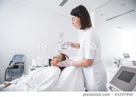 Young cosmetologist making injection in girl forehead 43297940