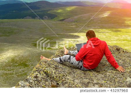 a man sits on a rock on a mountainside 43297968