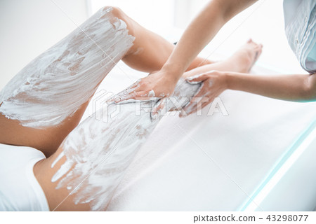 Beautician applying cosmetic mask on woman lower body 43298077