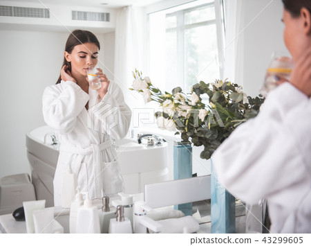 Orderly woman drinking delicious liquid in apartment Orderly woman drinking delicious liquid in apartment 43299605