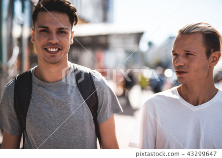 Optimistic friends speaking during sunny walk outdoor 43299647