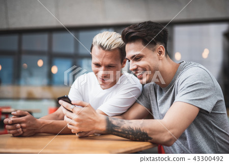 Optimistic males watching at digital device outside Optimistic males watching at digital device outside 43300492