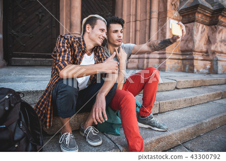 Cheerful men taking photo on phone outdoor Cheerful men taking photo on phone outdoor 43300792
