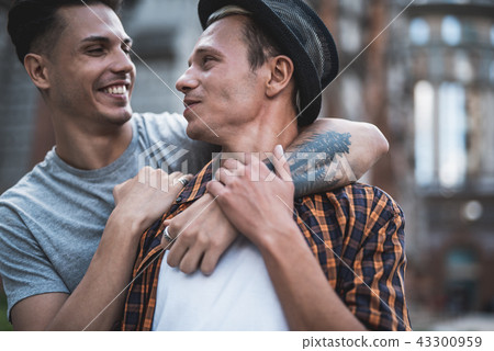Cheerful man embracing positive comrade during conversation 43300959