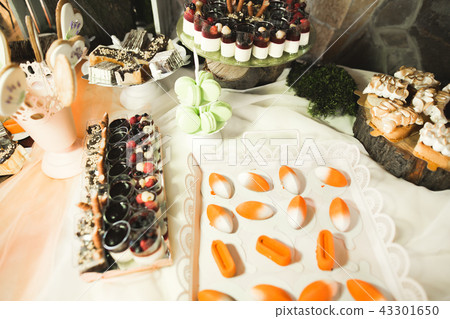 Delicious and tasty dessert table with cupcakes shots at reception closeup Delicious and tasty dessert table with cupcakes shots at reception closeup 43301650