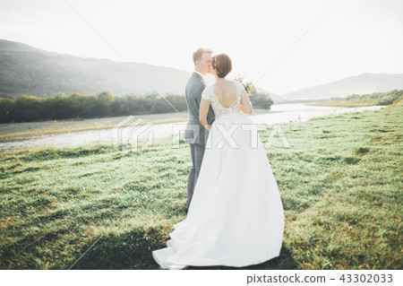 Gorgeous bride and stylish groom walking at sunny landscape, wedding couple, luxury ceremony Gorgeous bride and stylish groom walking at sunny landscape, wedding couple, luxury ceremony 43302033