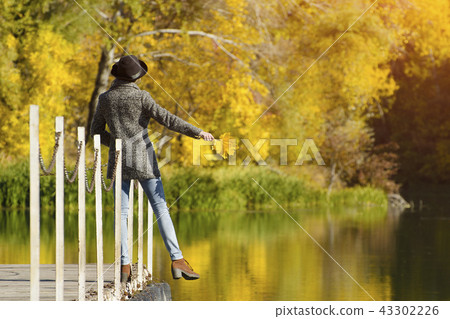 Girl in a hat with leaves in hands standing Girl in a hat with leaves in hands standing 43302226