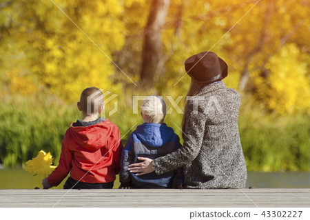 Mom and two children are sitting on the pier 43302227